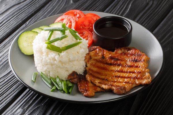 Vietnamese food broken rice with grilled pork and fresh vegetables close-up in a plate. horizontal Vietnamese food broken rice with grilled pork and fresh vegetables close-up in a plate on the table. horizontal